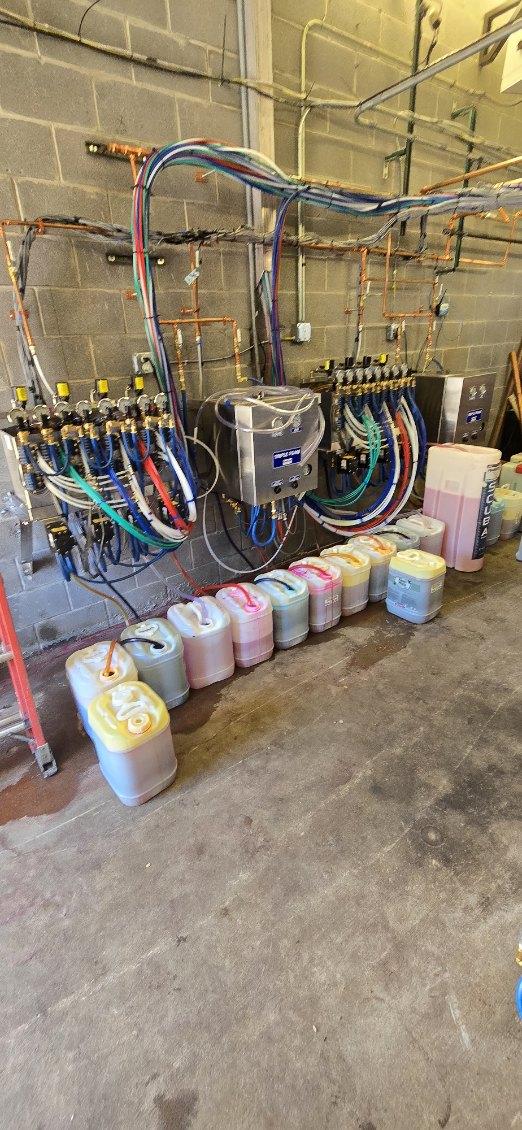 Carwash chemical containers and colored line manifold system mounted on a wall