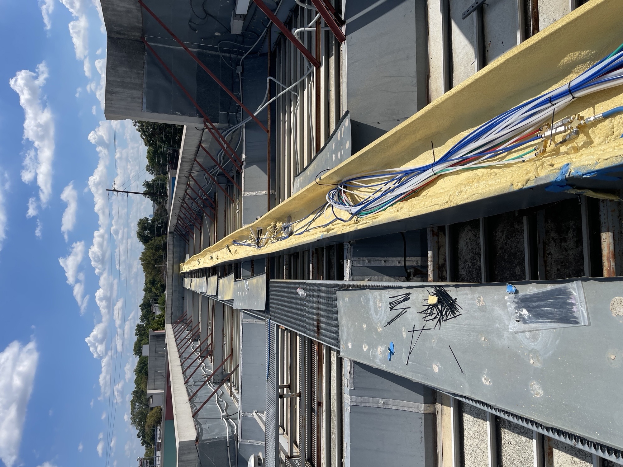 Rooftop carwash utility lines and conduit installation under a blue sky