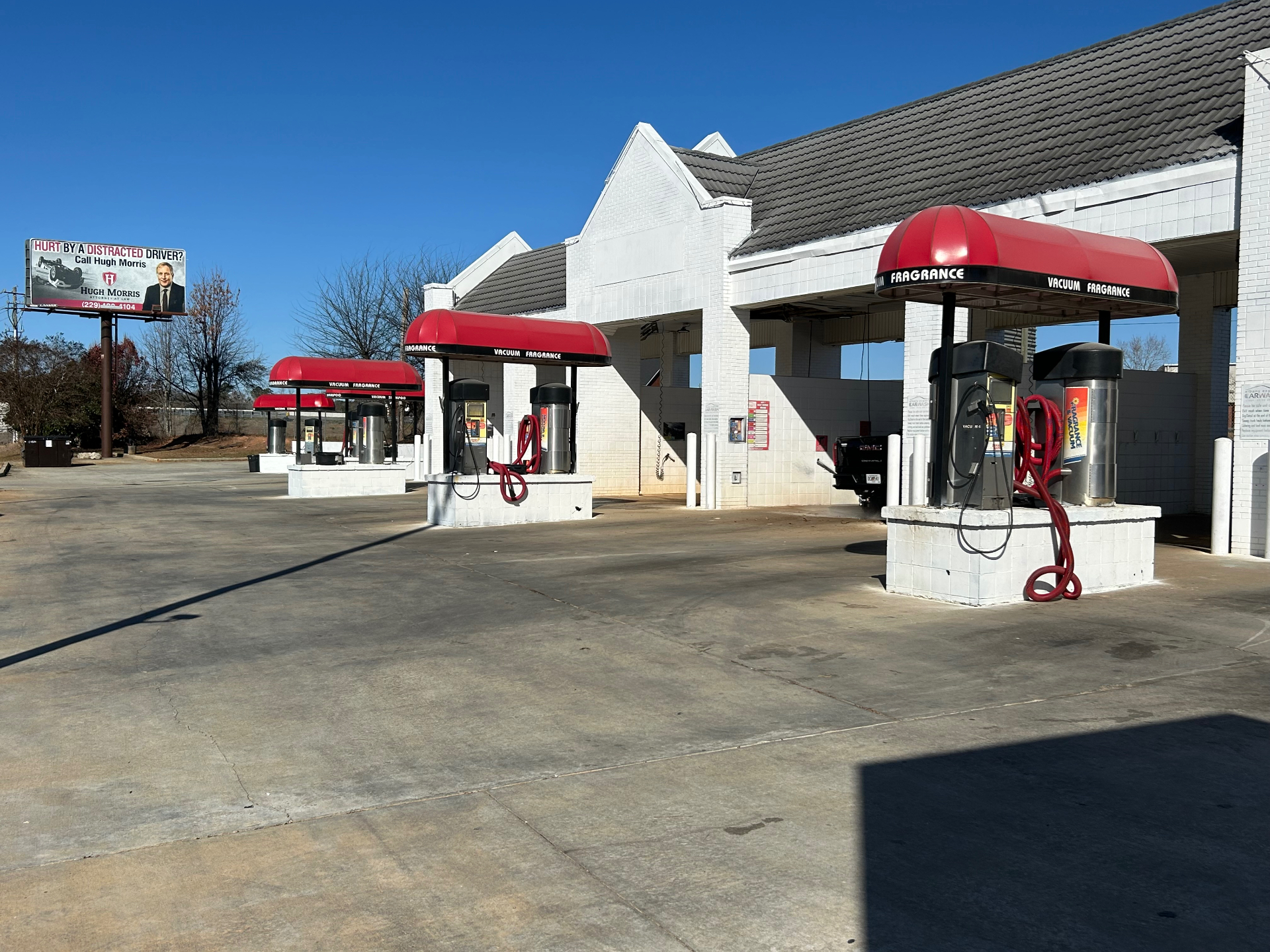 Outdoor carwash vacuum stations with red canopies beside wash bays